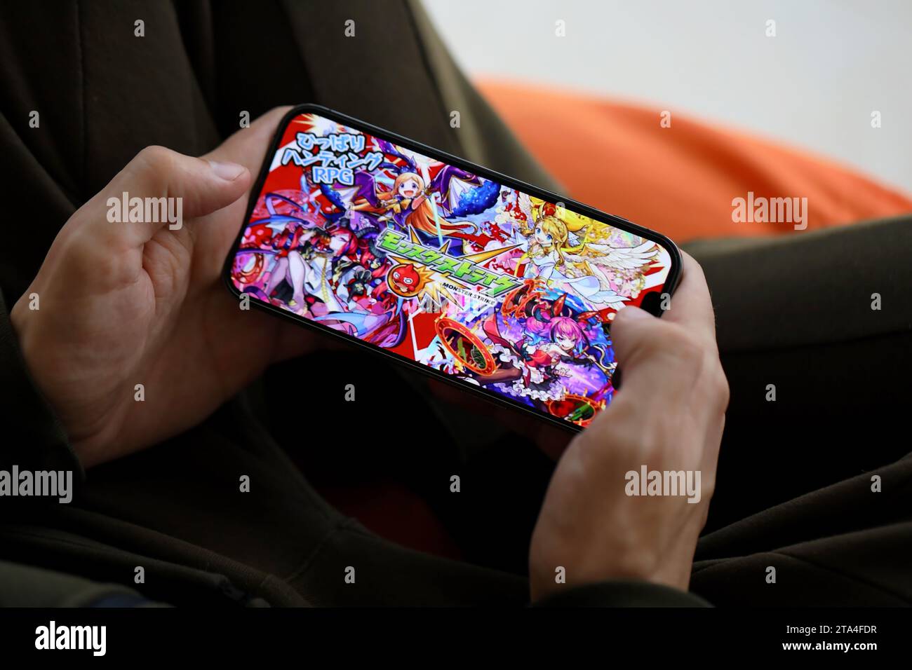 Monster Strike mobile iOS jeu sur iPhone 15 écran de smartphone dans les mains masculines pendant le gameplay mobile. Jeux et divertissements mobiles sur un appareil portable Banque D'Images