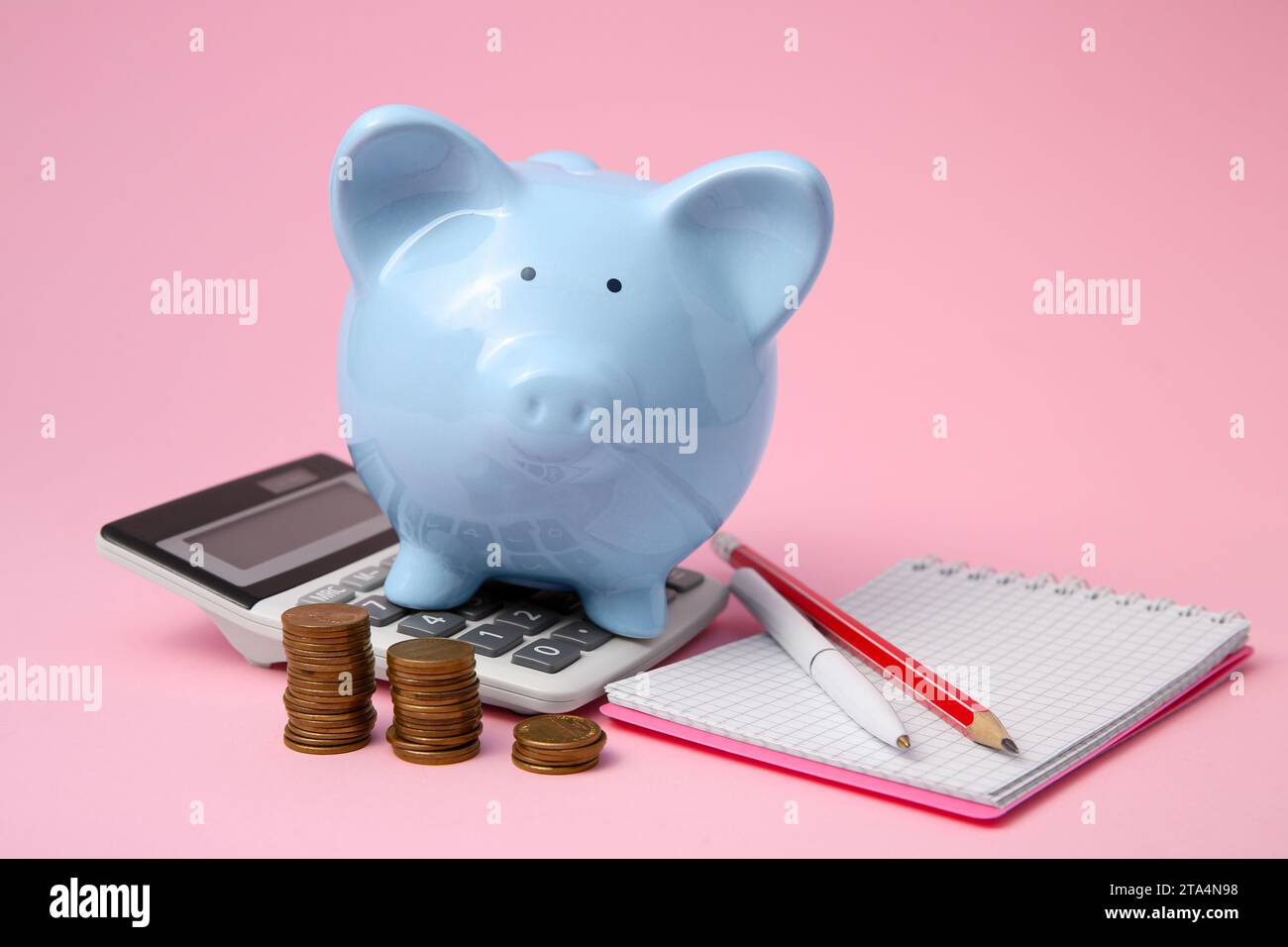 Tirelire, pièces de monnaie et papeterie sur fond rose Banque D'Images