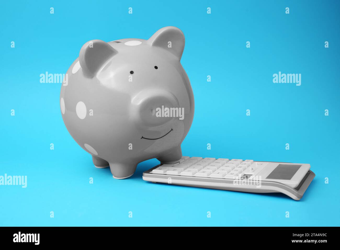 Tirelire et calculatrice sur fond bleu clair Banque D'Images