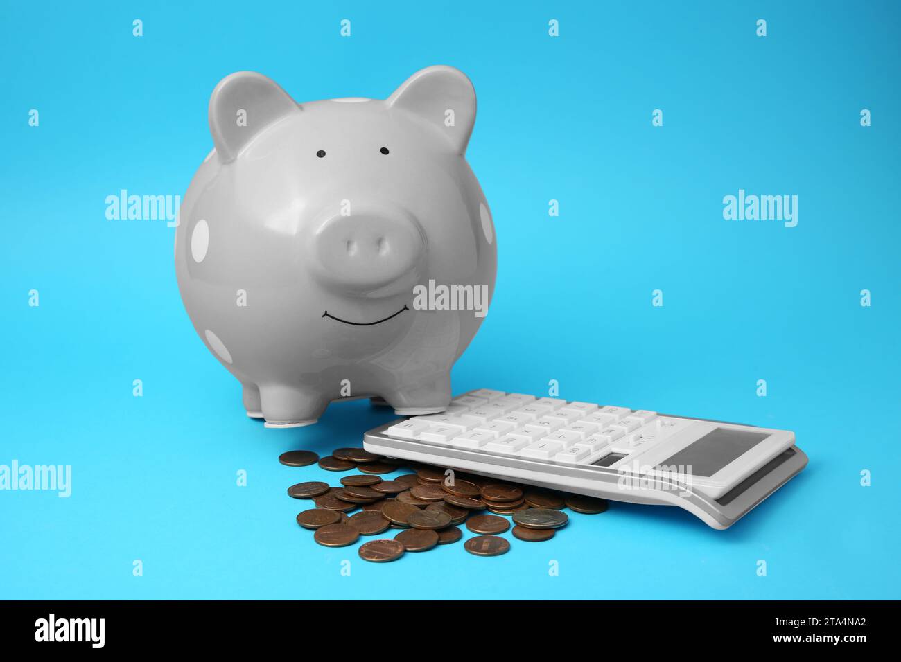 Tirelire, pièces de monnaie et calculatrice sur fond bleu clair Banque D'Images