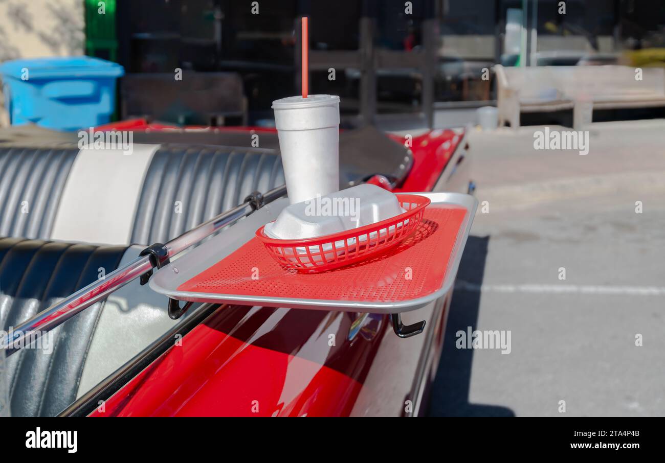 plateau de nourriture sur ancienne voiture vintage convertible rede avec tasse à boisson en styromousse paille rouge et support de hotdog en styromousse. Banque D'Images