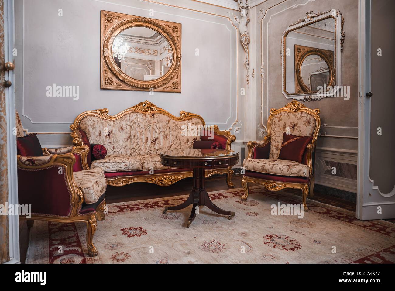 Chambre opulente de style vénitien, mobilier blanc et or orné, éclairage tamisé Banque D'Images