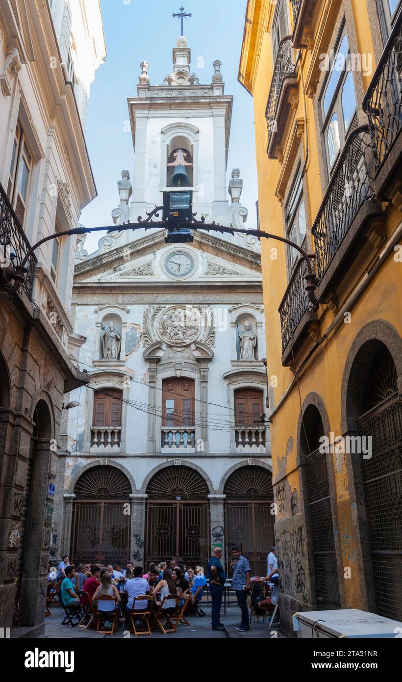 Les jeunes profitent de l’happy hour dans les bars de la Rua do Ouvidor (rue Ouvidor), en face de l’église Nossa Senhora da Lapa dos Mercadores. La rue est considérée comme la plus célèbre de la vieille ville (XVIII et XIX siècles), bordée de magasins de détail, cafés et bureaux de journaux. Elle a longtemps été une promenade favorite et occupe une place importante dans la vie sociale et politique de la ville. Banque D'Images