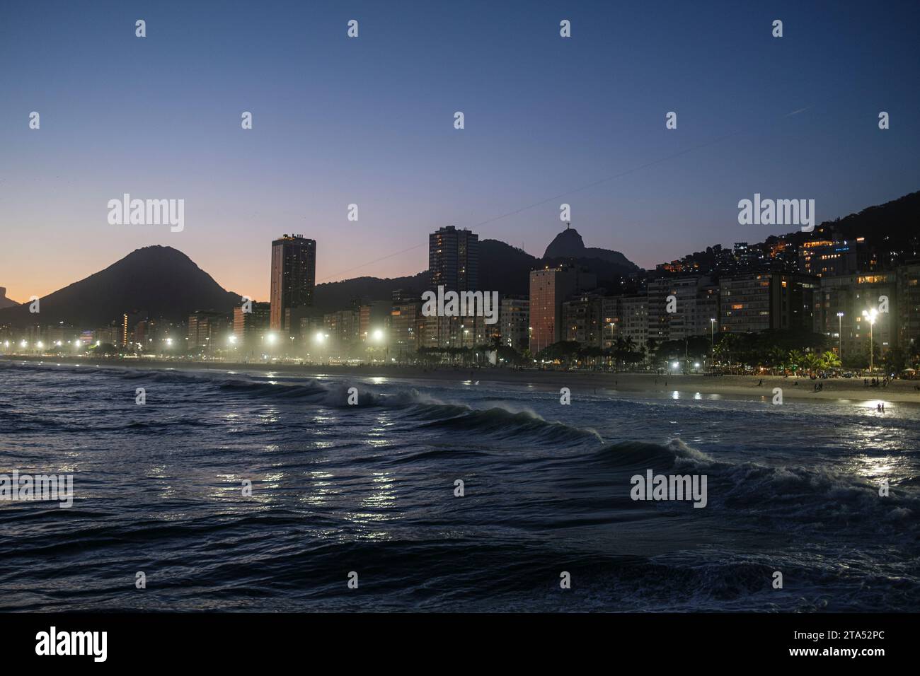 Leme et la plage de Copacabana au coucher du soleil, Rio de Janeiro, Brésil. Christ Rédempteur et Favela Morro da Babilonia à droite derrière les bâtiments du front de mer. Banque D'Images