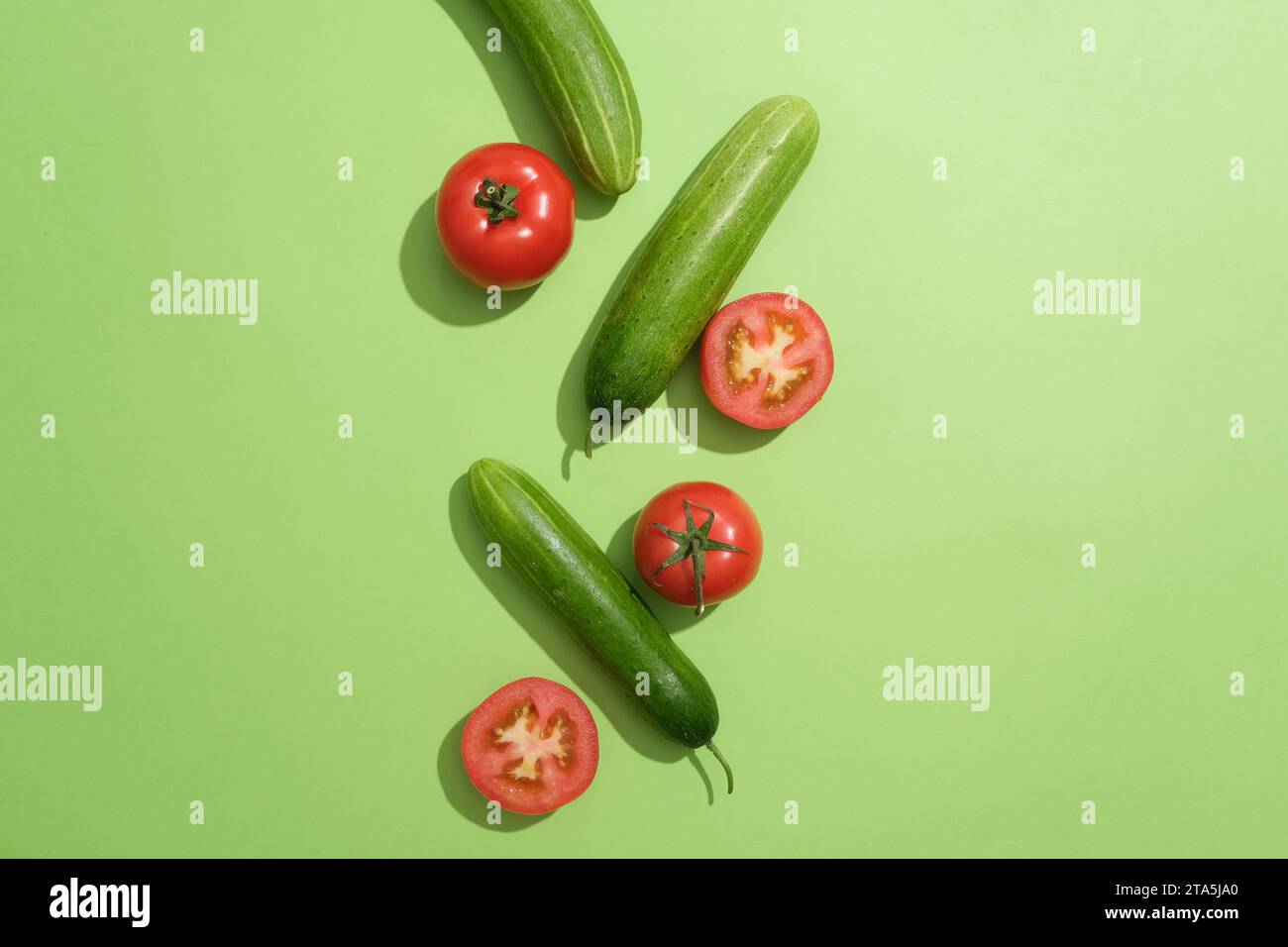 Le fond vert présentait des tomates fraîches coupées en deux et quelques concombres. Les enzymes présentes dans les tomates aident à exfolier doucement la peau Banque D'Images