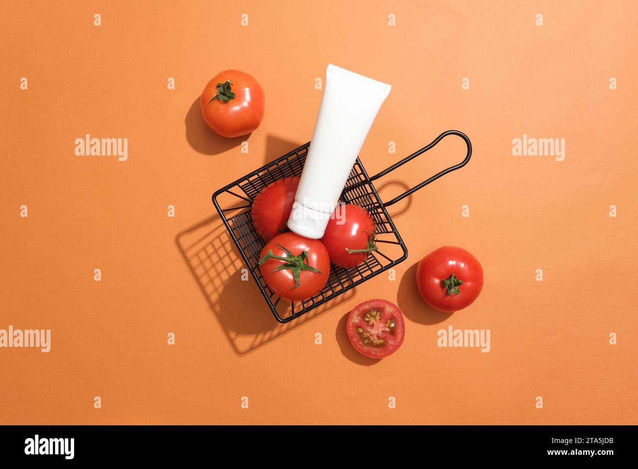 Un panier contenant des tomates fraîches avec une étiquette placée sur le dessus. Fond orange. La teneur en complexe de vitamine B présente dans les tomates aide à combattre t Banque D'Images