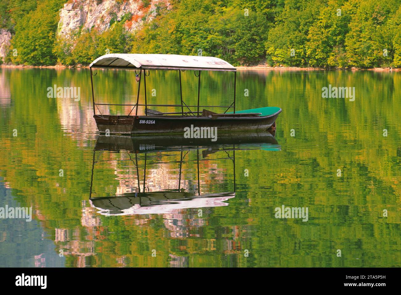 Vue automnale du vieux bateau avec canopée et reflet de la forêt sur l'eau douce du lac Perucac - rivière Drina, Bajina Basta, Serbie Banque D'Images