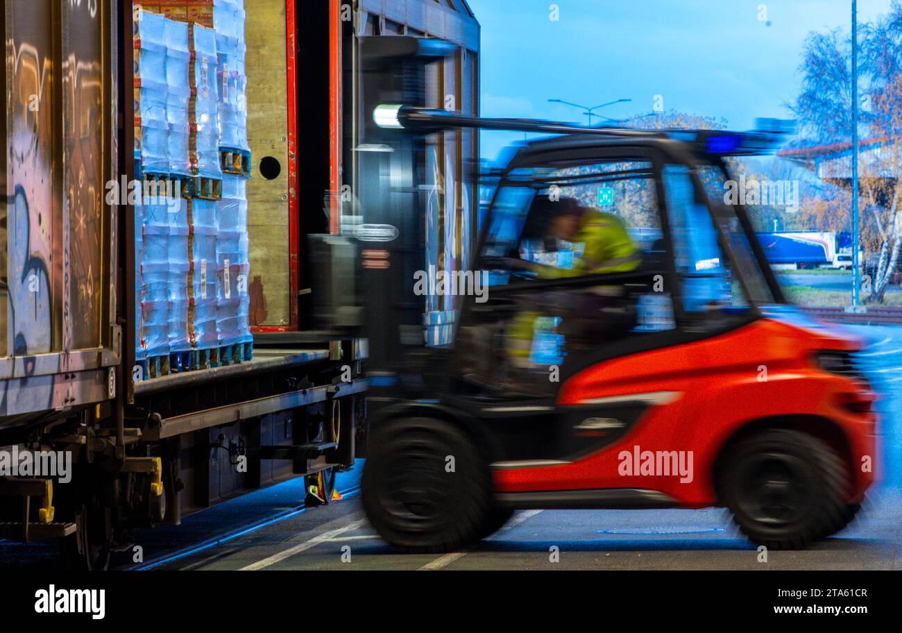 Rostock, Allemagne. 21 novembre 2023. Les palettes et les marchandises transportées sont rechargées dans des wagons par des remorques de la société logistique DB Schenker sur le site du centre logistique dans le port maritime. (Photo avec une longue durée d'exposition) la filiale logistique de Deutsche Bahn exploite plusieurs centres logistiques dans le Mecklembourg-Poméranie occidentale. Crédit : Jens Büttner/dpa/Alamy Live News Banque D'Images