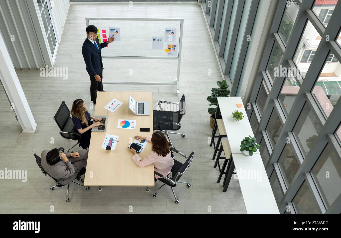 Un environnement de bureau montre un groupe de personnes assis autour d'une table, apparemment impliqués dans une discussion d'affaires sérieuse. Banque D'Images