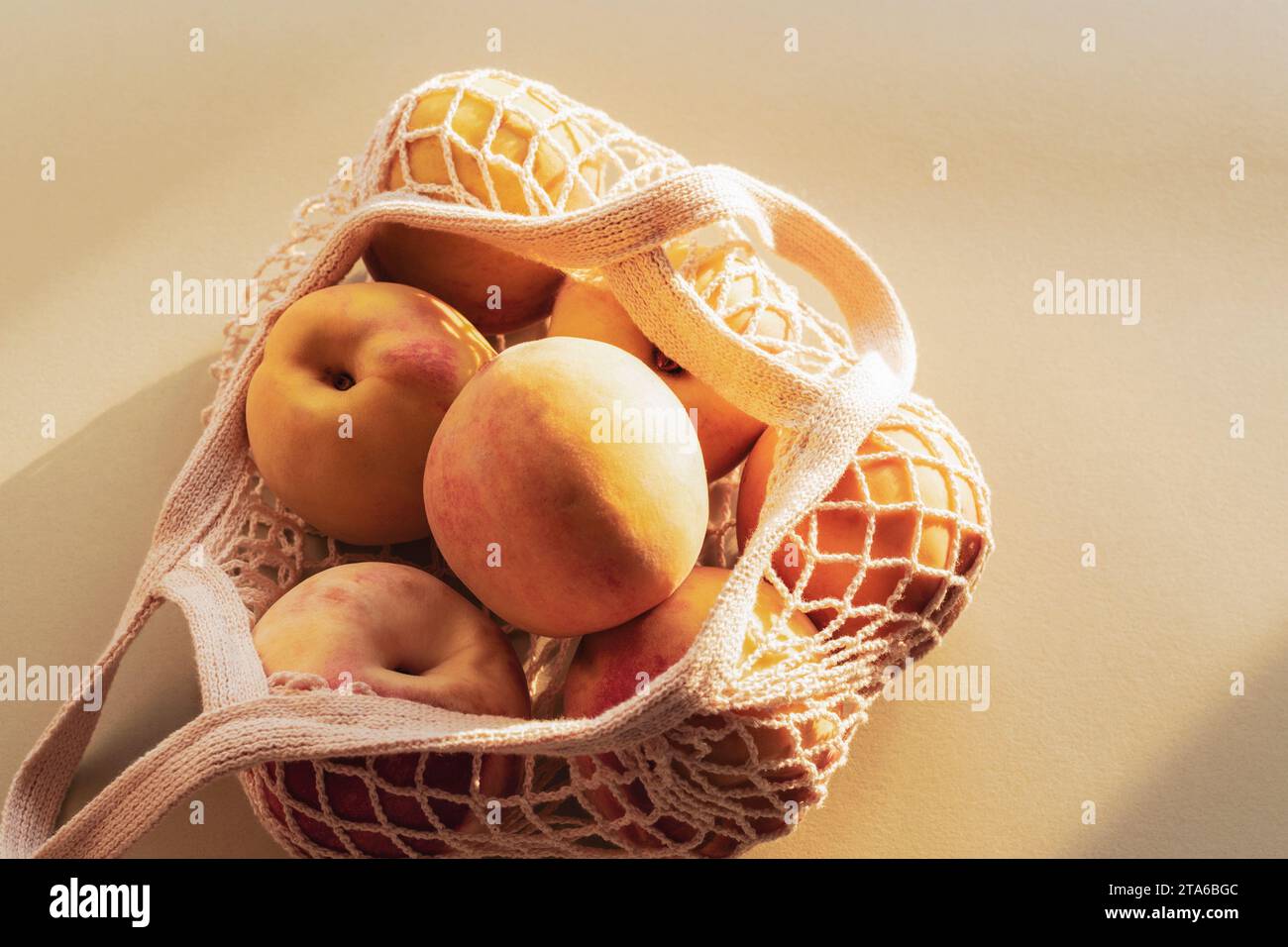 Pêches mûres fraîches dans un sac de ficelle à la lumière du soleil. Concept zéro déchet, alimentation saine. Vue de dessus, gros plan. Banque D'Images