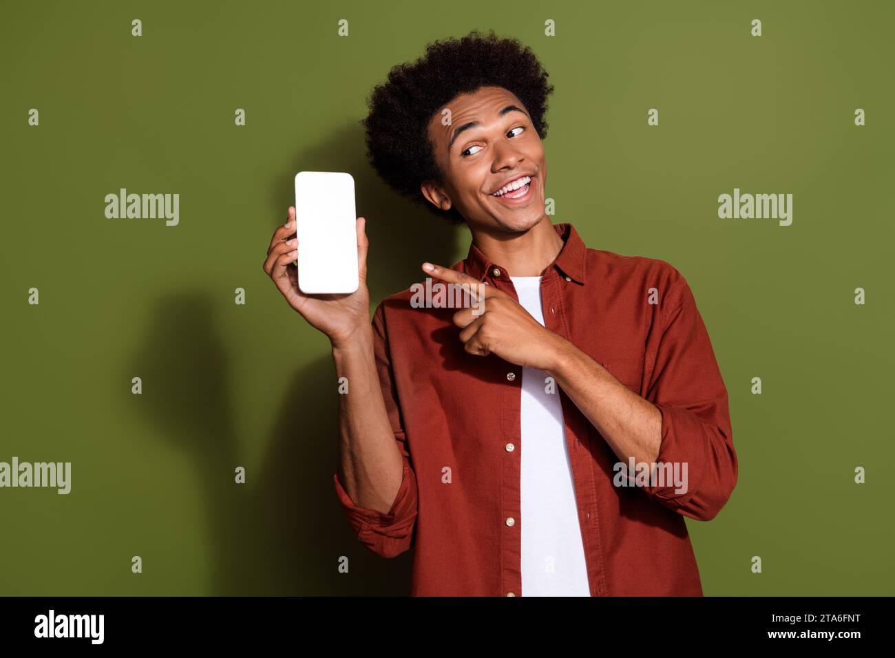Portrait de gars drôle porter chemise élégante dirigeant regarder le code qr sur l'écran de smartphone espace vide isolé sur fond de couleur verte Banque D'Images