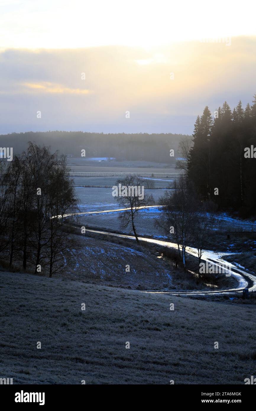 Route sinueuse et glacée en Finlande rurale par un matin d'hiver brumeux. Banque D'Images