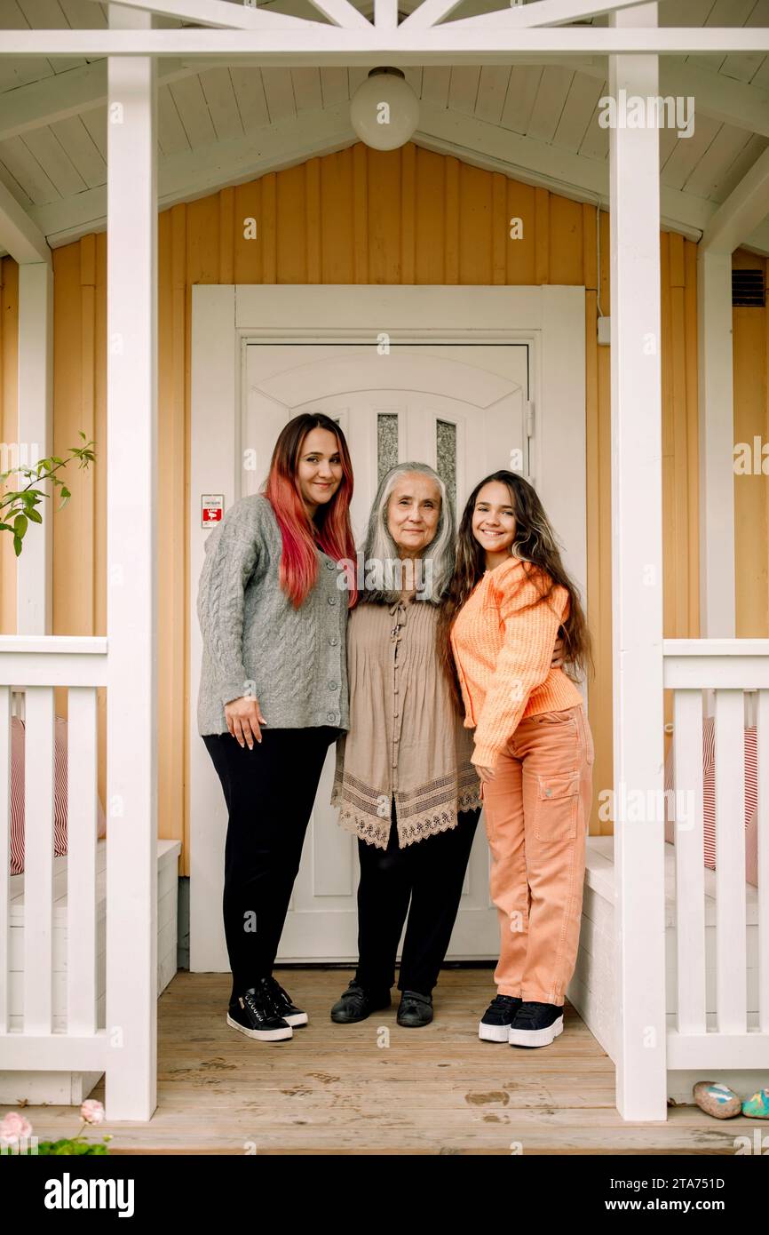 Portrait de femme aînée souriante avec fille et petite-fille debout au porche Banque D'Images