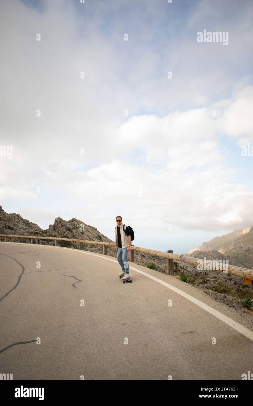 Homme mature skateboard sur la route contre le ciel Banque D'Images