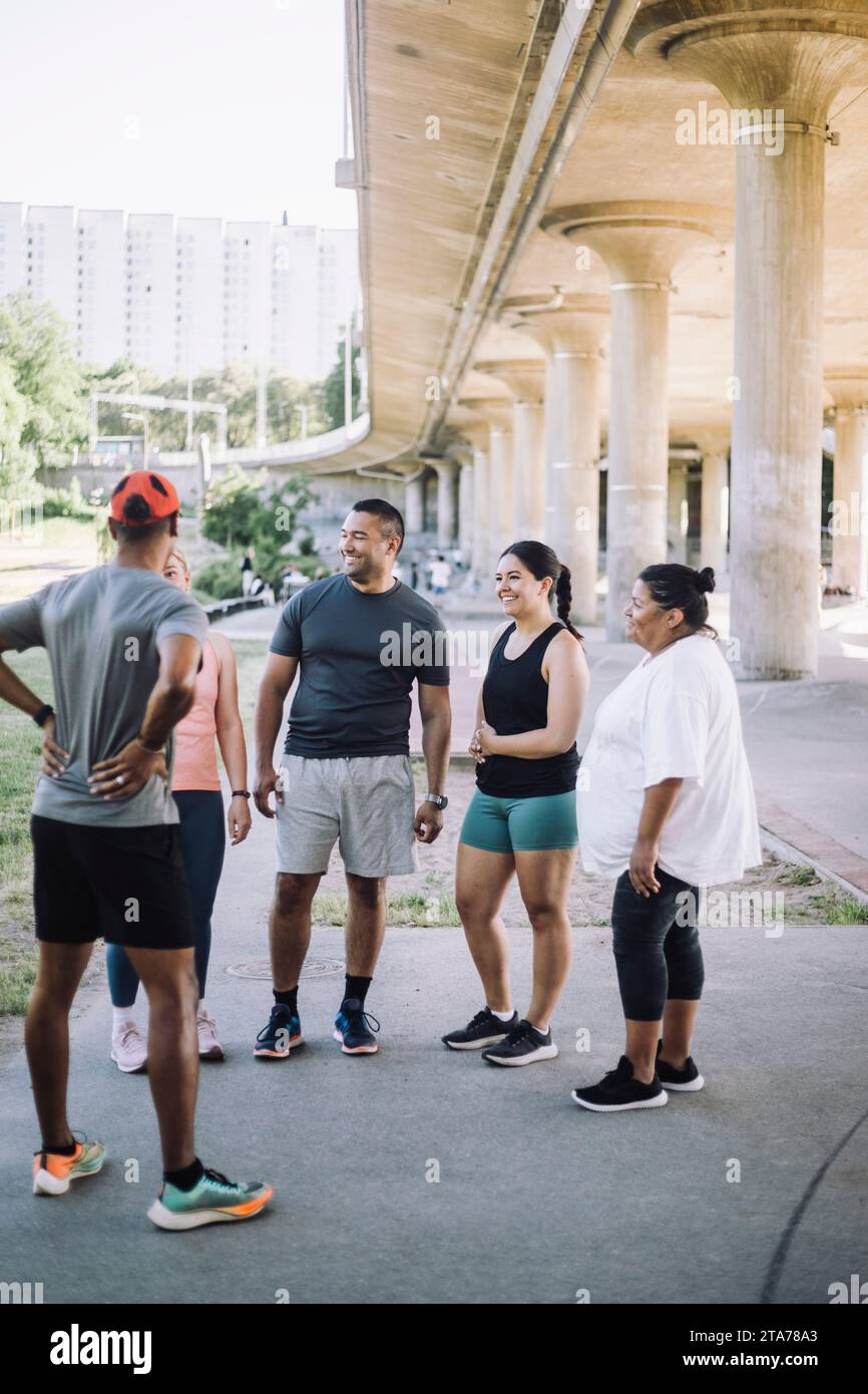 Souriant des amis multiraciaux masculins et féminins parlant entre eux après l'entraînement Banque D'Images