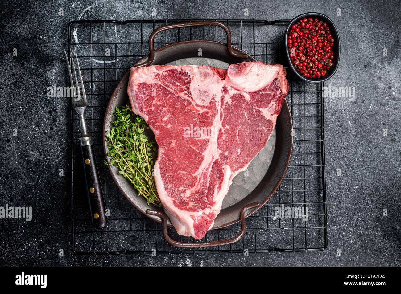 Viande de bœuf marbré fraîche brute en T Steak sur un plateau en acier Arrière-plan noir. Vue de dessus. Banque D'Images