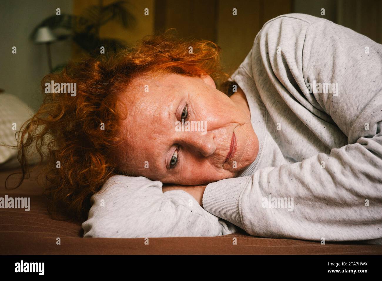 Triste femme âgée contemplant tout en étant couchée sur le lit à la maison Banque D'Images