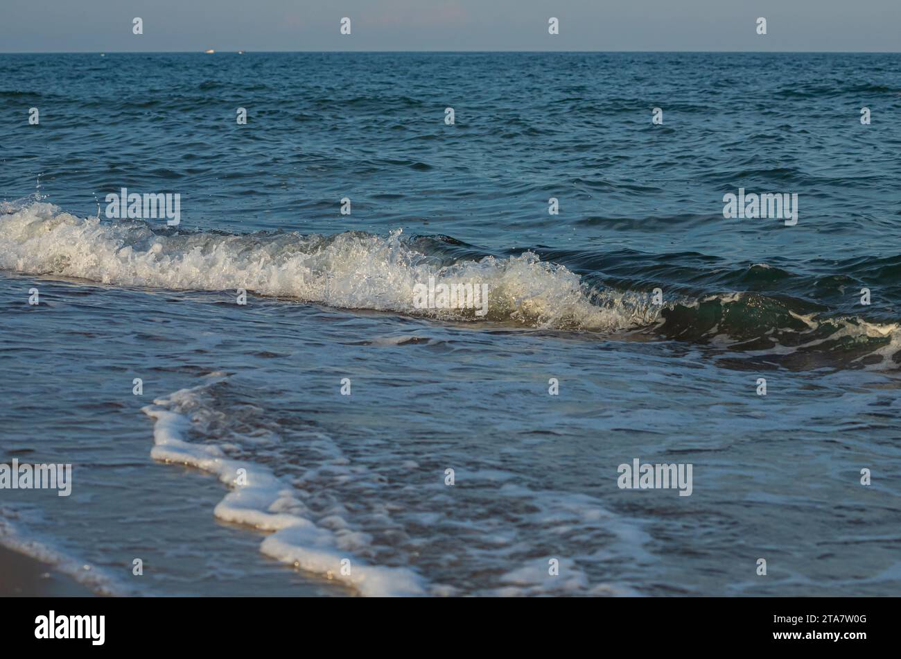 Une grande et forte onde de tempête de couleur turquoise avec des éclaboussures de mousse blanche coule et se brise sur le rivage. Banque D'Images