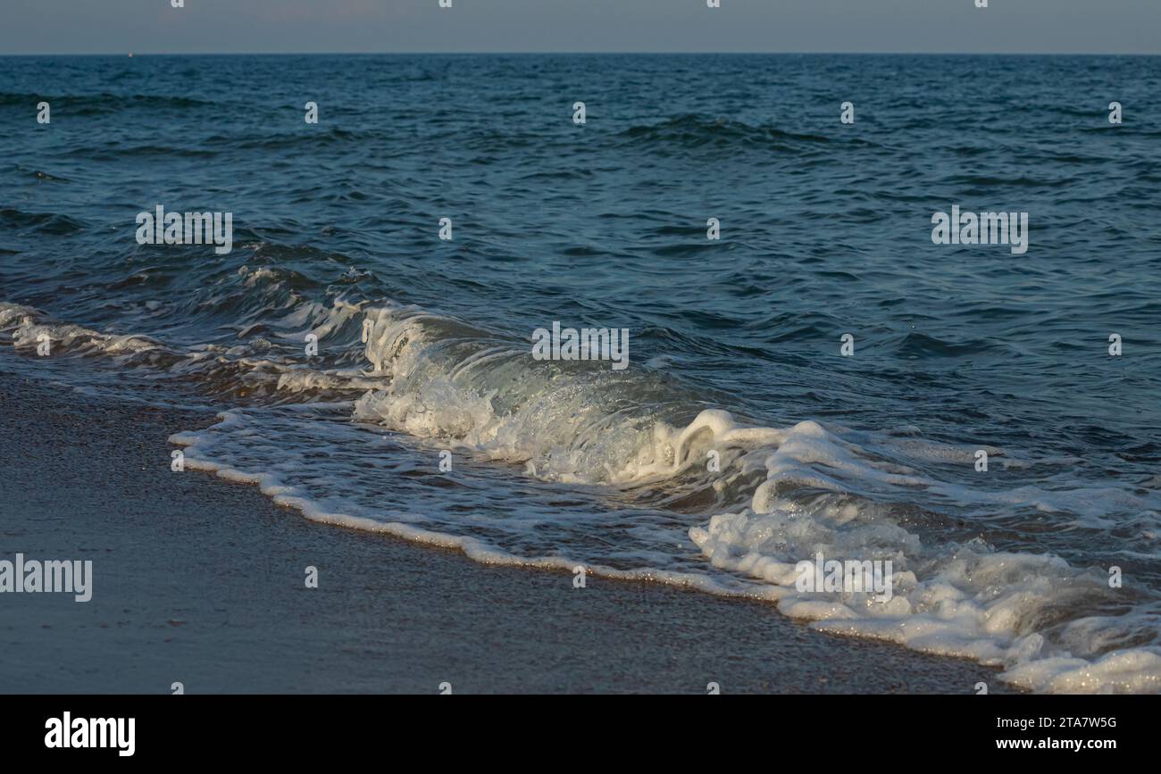 Une grande et forte onde de tempête de couleur turquoise avec des éclaboussures de mousse blanche coule et se brise sur le rivage. Banque D'Images