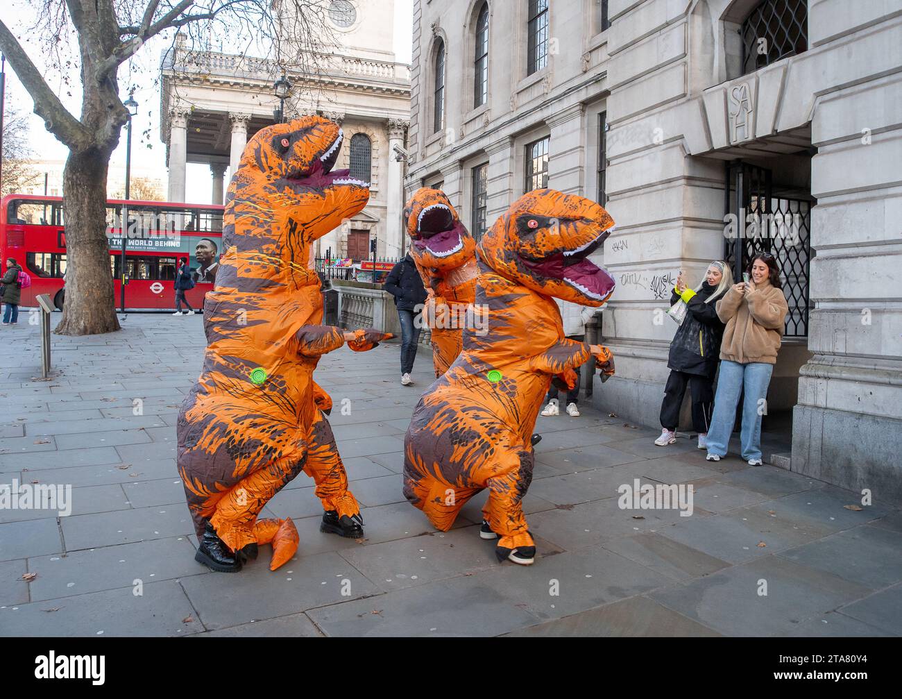 Londres, Royaume-Uni. 28 novembre 2023. Dancing Dinasours se produisaient aujourd'hui à Londres par Trafalgar Square. Ils ont peut-être été des danseurs de la comédie musicale The Lion King du West End. Des manifestants anti-zone d'ultra-faible émission ont également été vus à Londres à plusieurs reprises, déguisés en dinasours bloquant les fourgonnettes mobiles de l'ULEZ prenant des images de voitures dans les zones de l'ULEZ. Crédit : Maureen McLean/Alamy Live News Banque D'Images