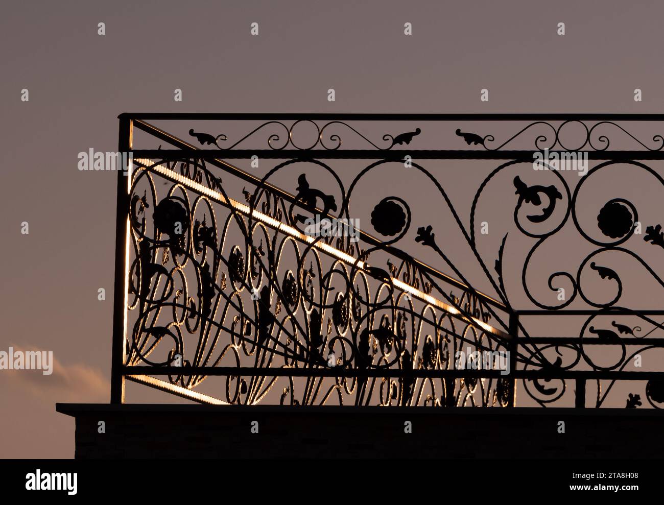 Clôture forgée noire, partie de la clôture du balcon. Illuminé par la lumière du soleil. Au coucher du soleil. Banque D'Images
