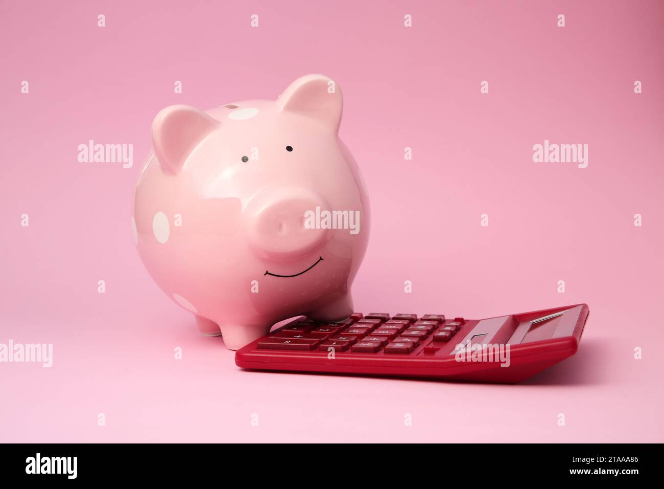 Tirelire et calculatrice sur fond rose Banque D'Images