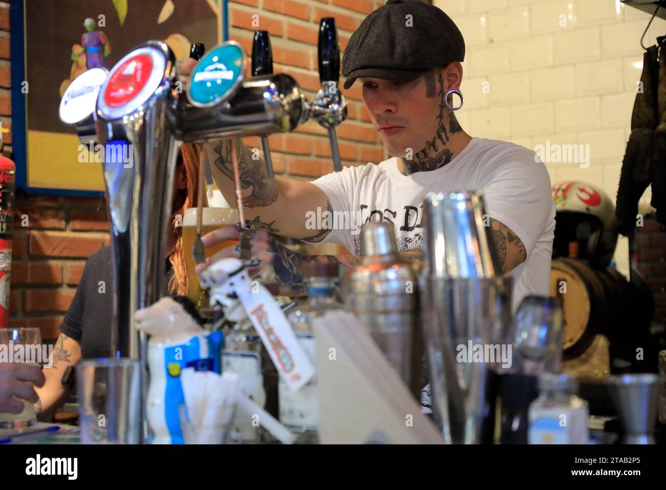 Un barman avec tatouage de cou versant de la bière dans un bar à l'intérieur de San Telmo Market.Buenos Aires.Argentina Banque D'Images