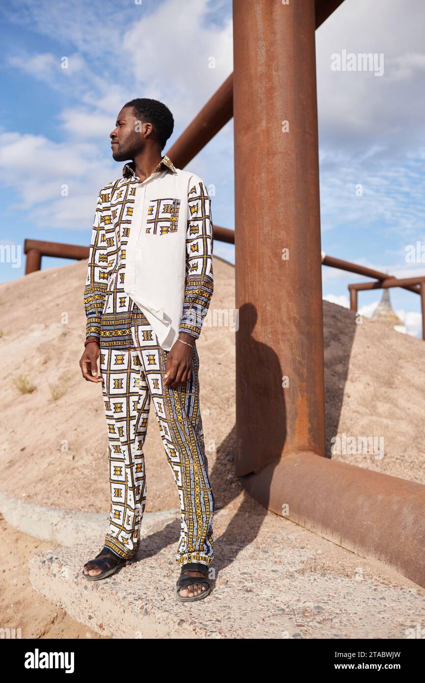 Portrait de mode pleine longueur de l'homme afro-américain portant la tenue avec le motif traditionnel dans le soleil du désert Banque D'Images