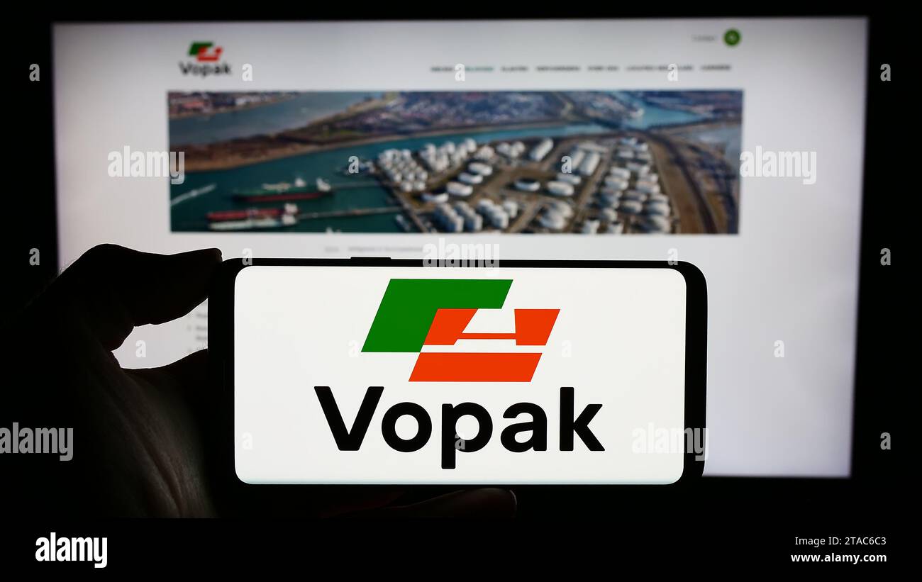 Personne détenant un téléphone portable avec le logo de la société de stockage néerlandaise Koninklijke Vopak N.V. devant la page Web de l'entreprise. Concentrez-vous sur l'affichage du téléphone. Banque D'Images