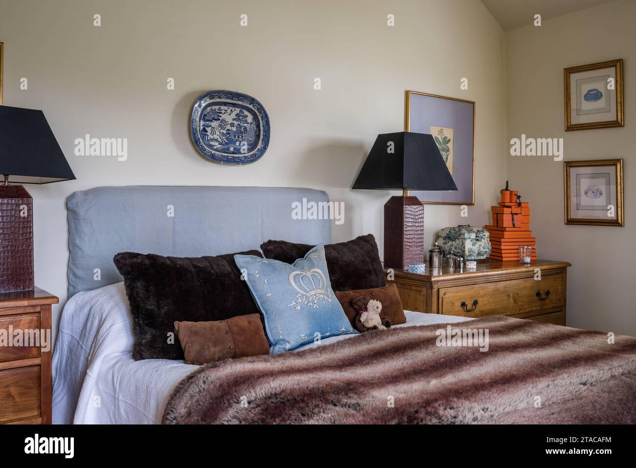 Paire de lampes avec jeté de fourrure et coussins dans une maison de plain-pied de style colonial. Truro, Cornouailles, Royaume-Uni. Banque D'Images