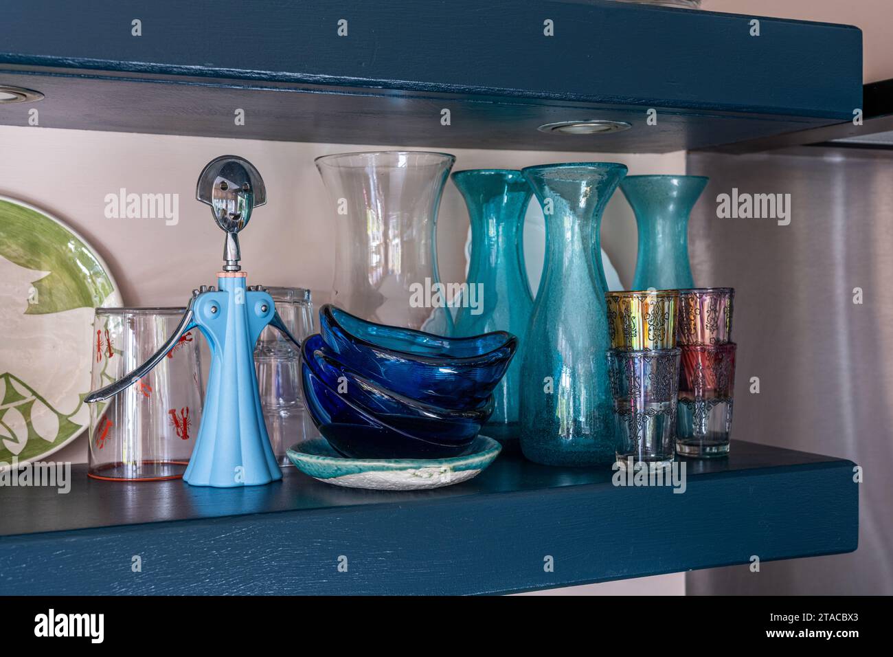 Verrerie vintage bleue et ouvre-bouteille sur étagère dans une maison de style Arts and Crafts des années 1930. Hove, East Sussex, Royaume-Uni. Banque D'Images