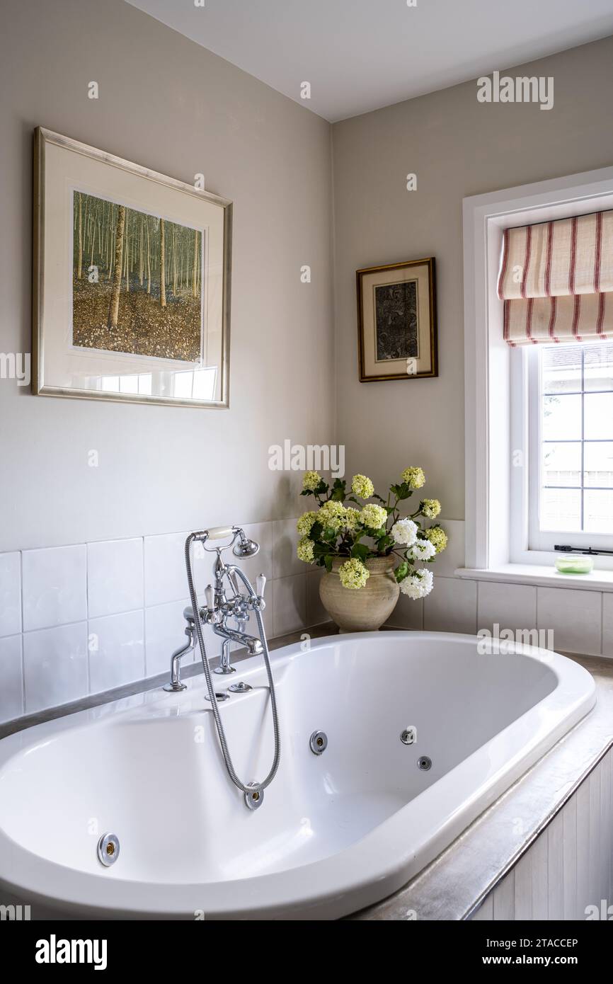 Fleurs dans le vase sur le bain jacuzzi entourent dans la maison de style Arts and Crafts des années 1930. Hove, East Sussex, Royaume-Uni. Banque D'Images