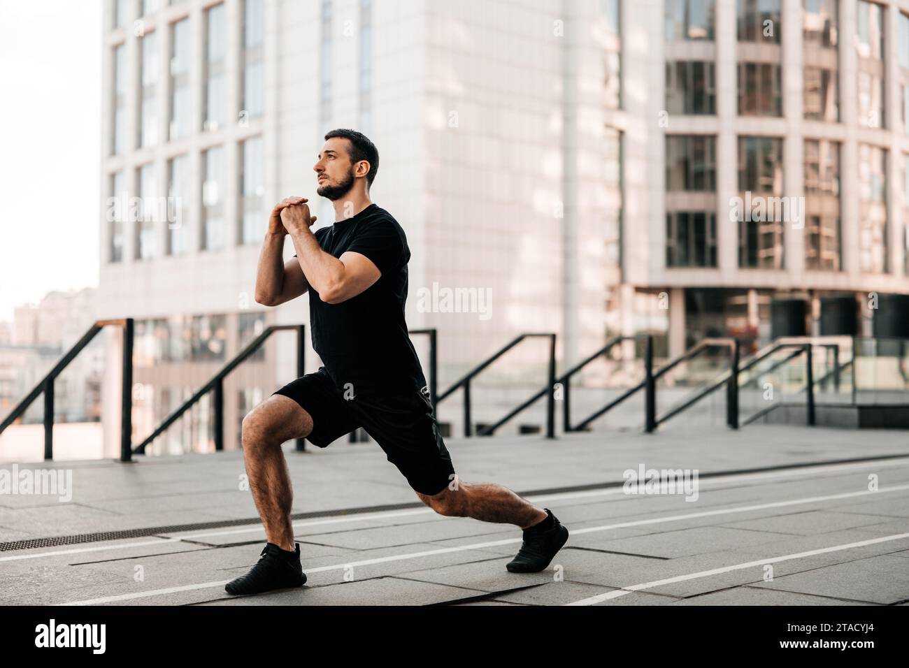 Faites avancer l'homme qui fait une fente. Le sport dans le concept de la grande ville. Homme fort qui étire les jambes avant de faire du jogging. Concept de soins de santé. Coureur de sport noir. Urb Banque D'Images