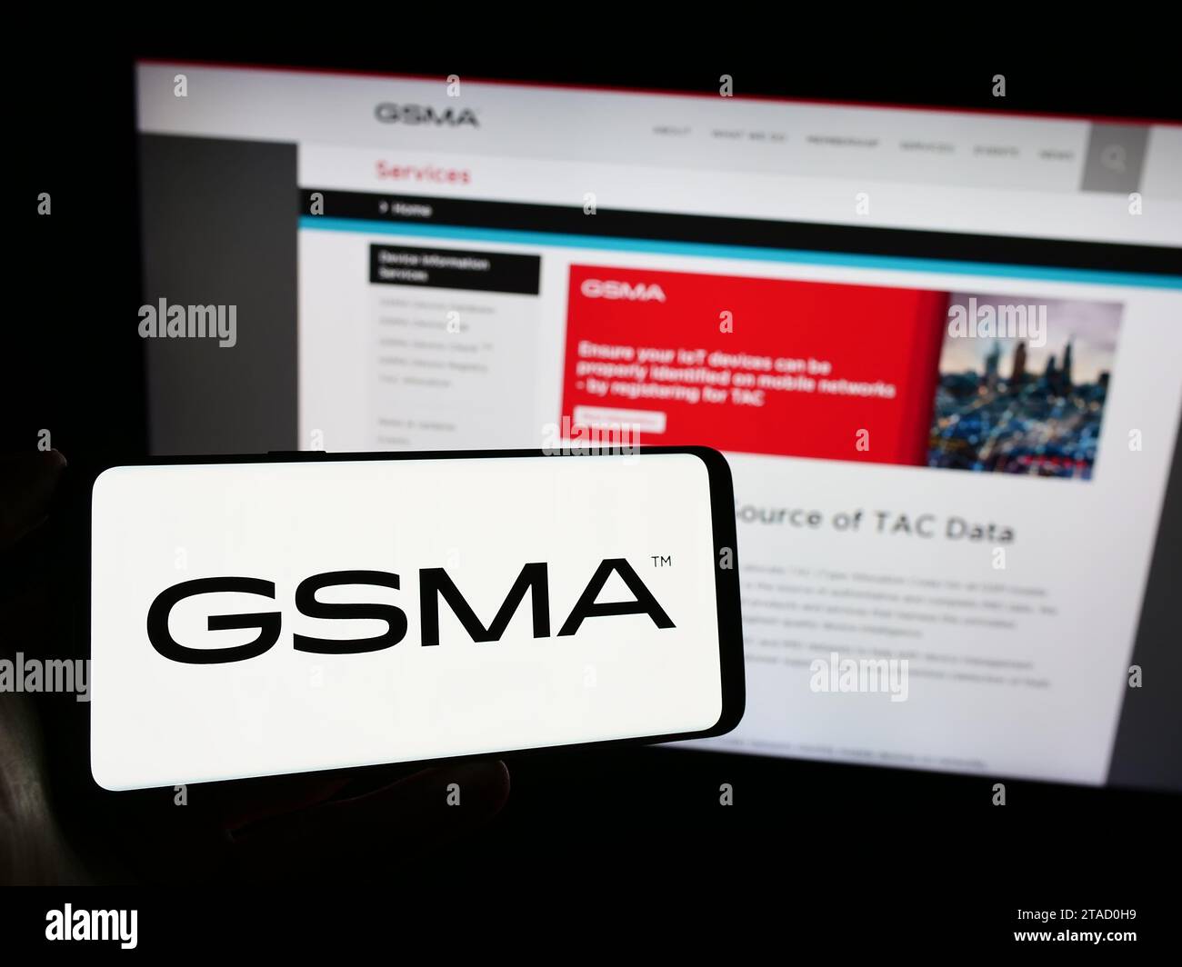 Personne détenant un téléphone portable avec le logo de l'organisation de l'industrie mobile GSM Association (GSMA) devant la page Web de l'entreprise. Concentrez-vous sur l'affichage du téléphone. Banque D'Images