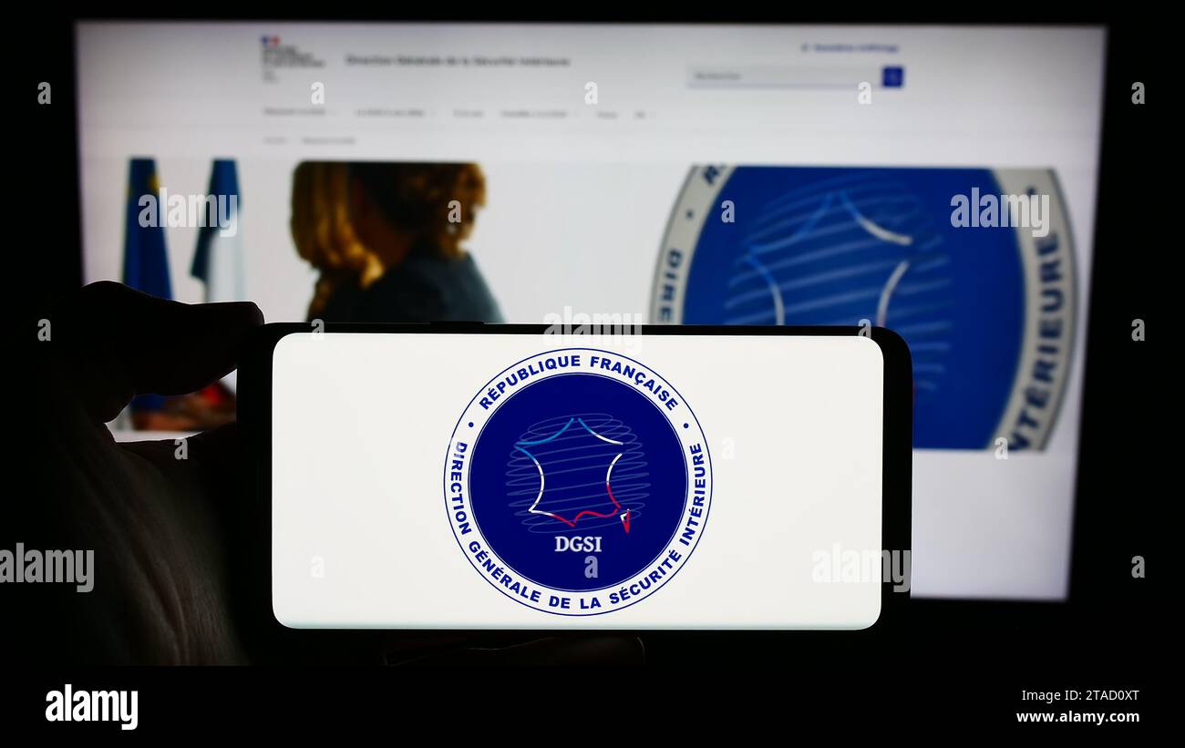 Personne tenant un téléphone portable avec le logo de la Direction générale de la sécurité intérieure (DGSI) devant la page Web. Concentrez-vous sur l'affichage du téléphone. Banque D'Images