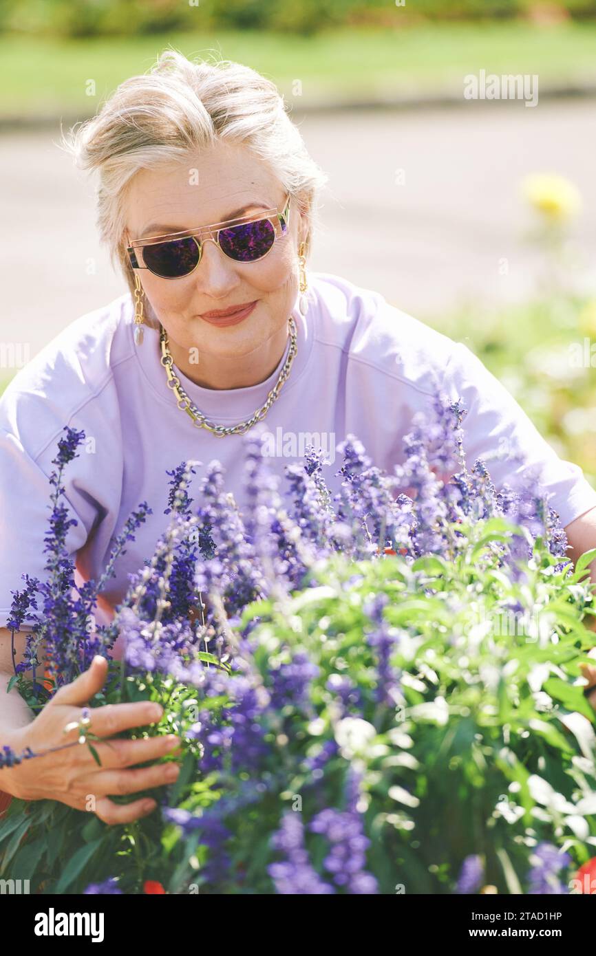 Portrait en plein air de femme âgée heureuse profitant d'une belle journée dans le jardin d'été Banque D'Images