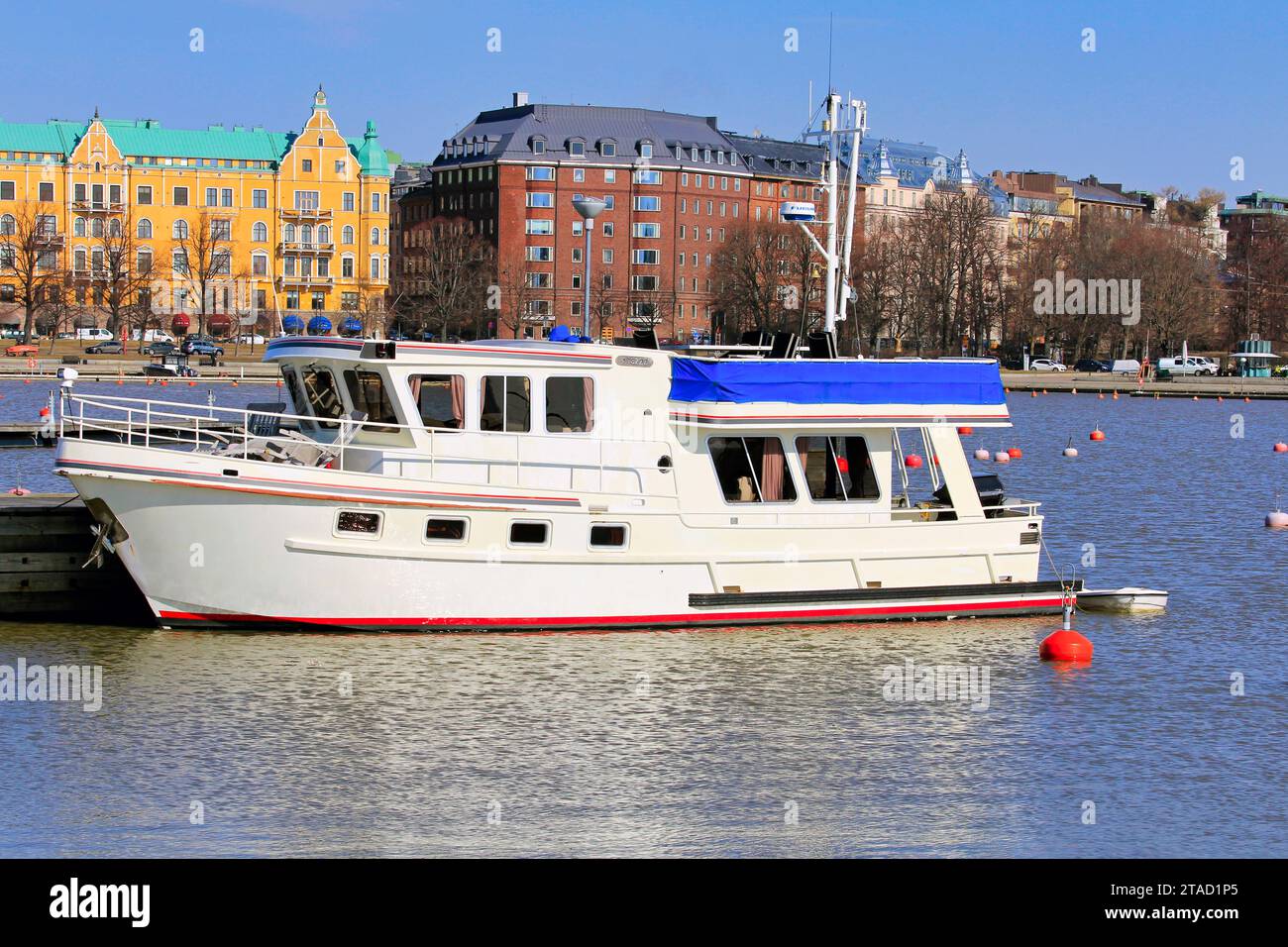Bateau de plaisance blanc amarré à la marina par une journée ensoleillée du printemps. En arrière-plan, front de mer Merisatama et Compass Square, Helsinki, Finlande. Banque D'Images
