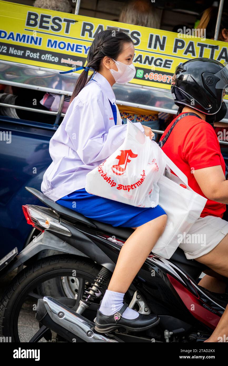 Une écolière thaïlandaise est assise à l'arrière d'un taxi moto voyageant à travers les rues animées de la ville de Pattaya, Bangkok. Banque D'Images