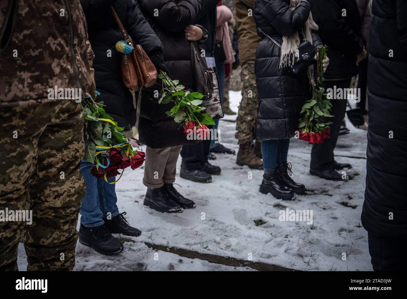 Kiev, Ukraine. 29 novembre 2023. Les personnes en deuil tiennent des fleurs et se tiennent debout dans la neige lors des funérailles du soldat ukrainien Serhiy Pavlichenko, mort au combat dans la région de Zaporizhjhia lors de l'invasion continue de l'Ukraine par la Russie, dans un cimetière militaire de Kiev. Depuis que la Russie a commencé son invasion à grande échelle de l'Ukraine le 24 février 2022, des dizaines de milliers de militaires ukrainiens et russes ont été tués. (Photo Laurel Chor/SOPA Images/Sipa USA) crédit : SIPA USA/Alamy Live News Banque D'Images