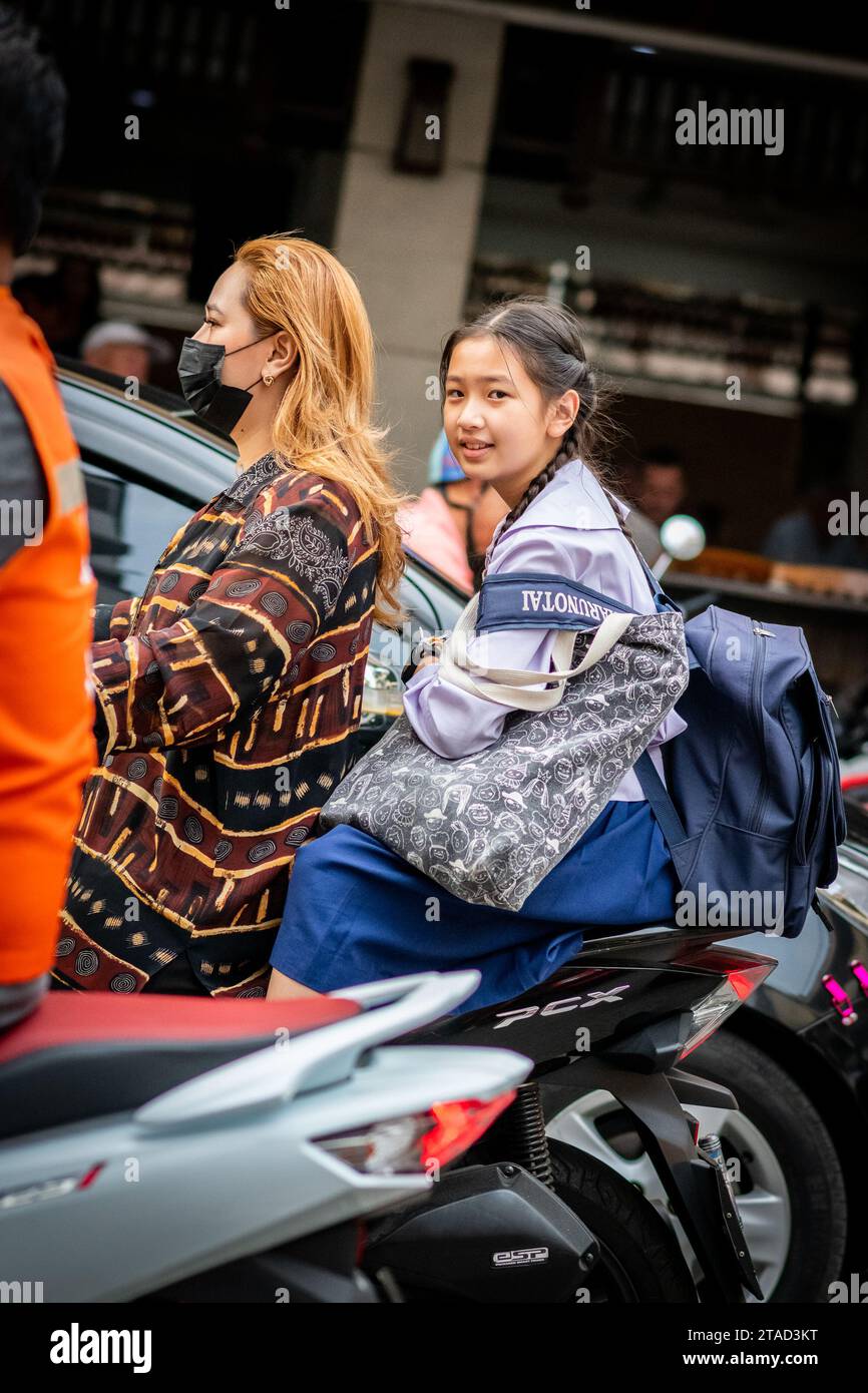 Une écolière thaïlandaise est assise à l'arrière d'un taxi moto voyageant à travers les rues animées de la ville de Pattaya, Bangkok. Banque D'Images