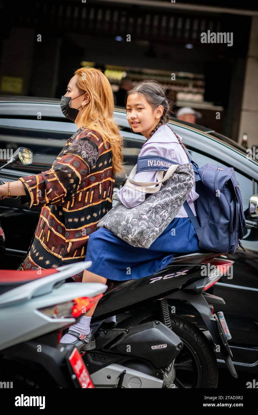 Une écolière thaïlandaise est assise à l'arrière d'un taxi moto voyageant à travers les rues animées de la ville de Pattaya, Bangkok. Banque D'Images