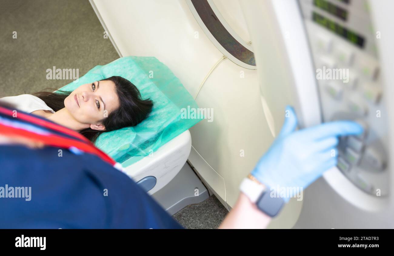 Un technologue en acquisition CT qui regarde le patient dans le scanner de tomodensitométrie pendant la préparation de la procédure. Femme entrant dans le scanner CT. Banque D'Images
