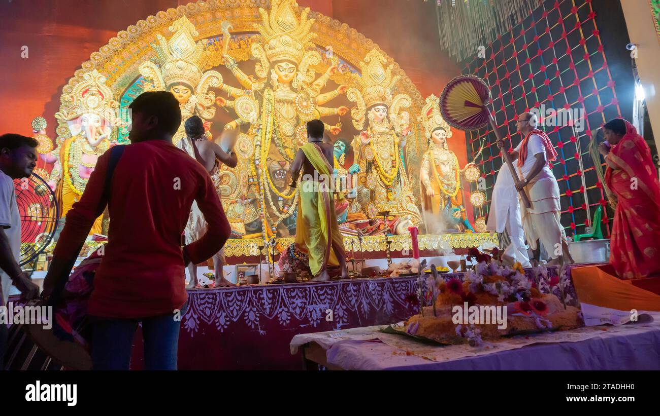 Howrah, Bengale occidental, Inde - 5 octobre 2022 : les Purohits hindous offrent du VOG, de la nourriture sucrée sacrée à la déesse Durga pendant que Dhaakis joue des dhaaks. Banque D'Images