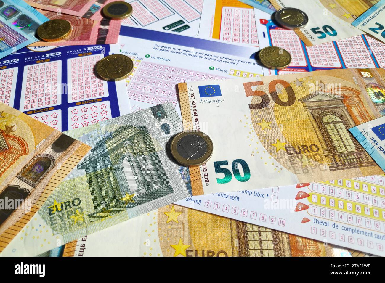 Paris, France - 21 septembre 2022 : quelques pièces et billets en euros au-dessus d'une pile de billets de loterie. Banque D'Images