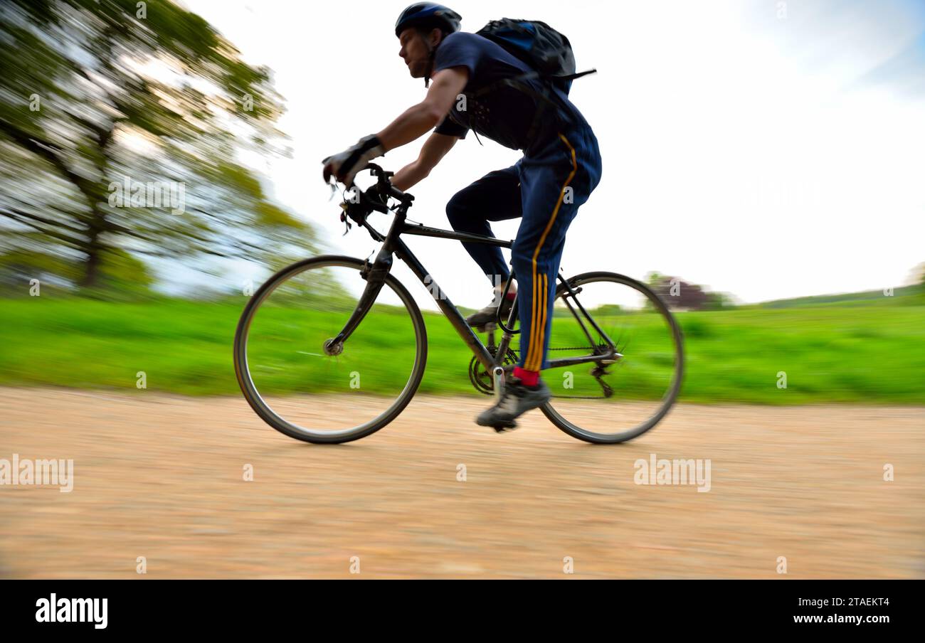 Un homme fait du vélo le long de l'un des chemins de gravier de Hampstead Heath dans le nord de Londres Royaume-Uni Banque D'Images