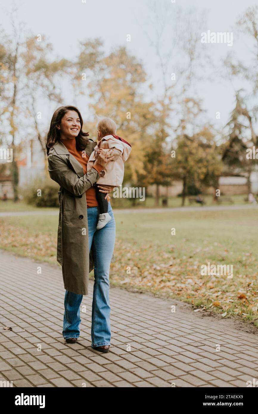 Jeune femme tenant une petite fille mignonne dans le parc d'automne Banque D'Images