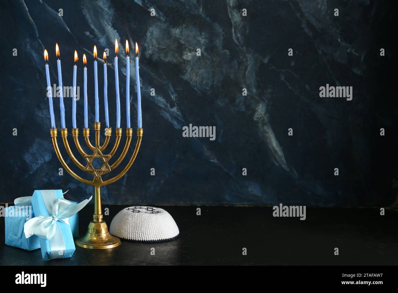 Menorah avec des bougies allumées, des cadeaux et une kippah pour la célébration Hanukkah sur fond sombre Banque D'Images