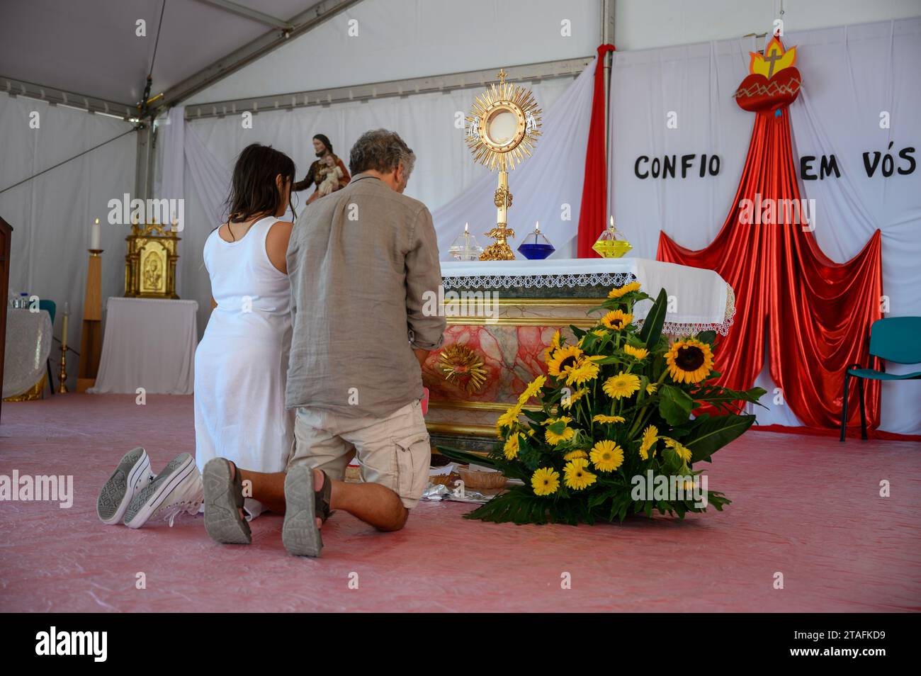 Un couple d'âge moyen agenouillé dans l'adoration du Saint Sacrement. Une tente au Sanctuaire du Christ Roi à Lisbonne, Portugal pendant les JMJ 2023. Banque D'Images