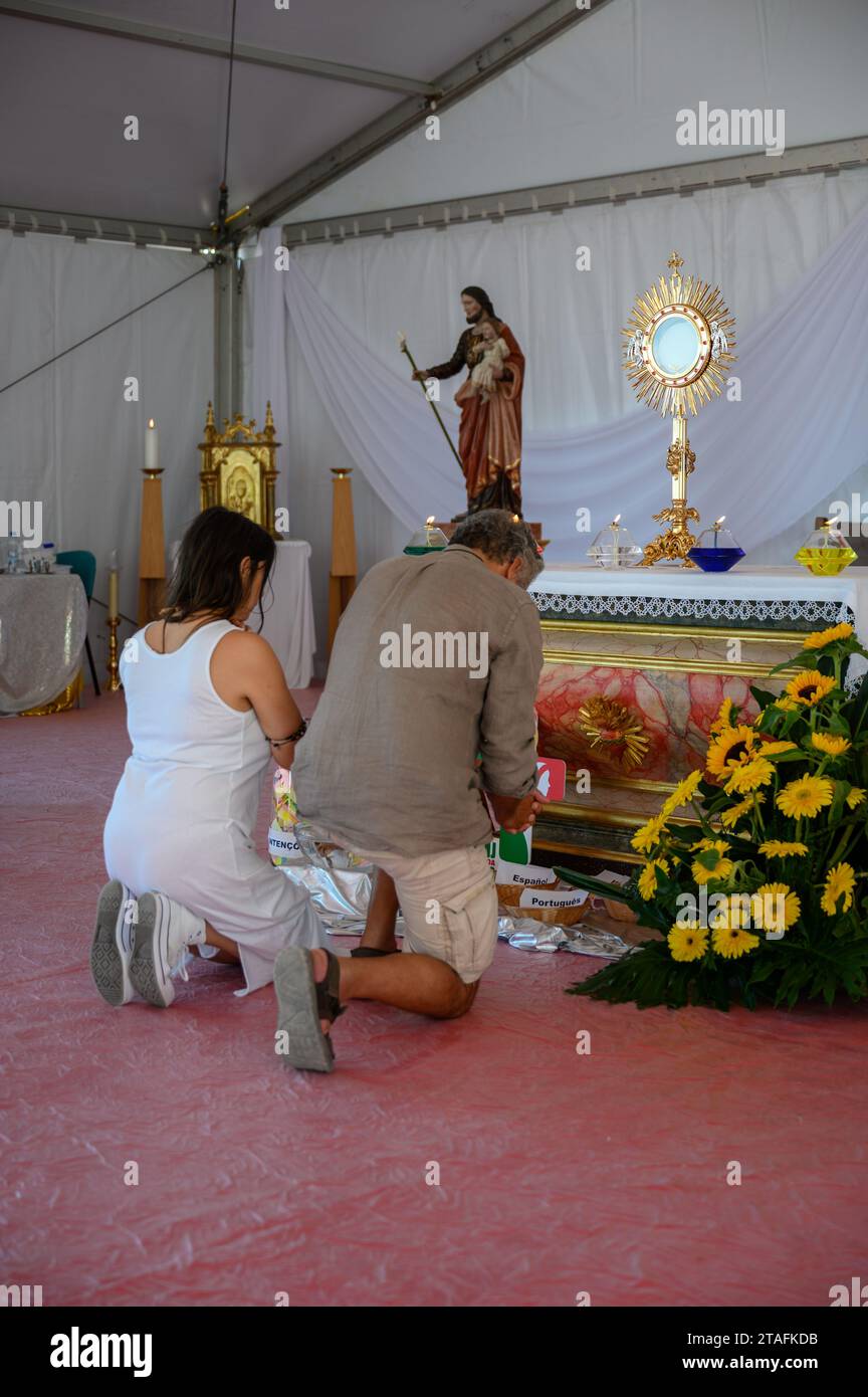 Un couple d'âge moyen agenouillé dans l'adoration du Saint Sacrement. Une tente au Sanctuaire du Christ Roi à Lisbonne, Portugal pendant les JMJ 2023. Banque D'Images