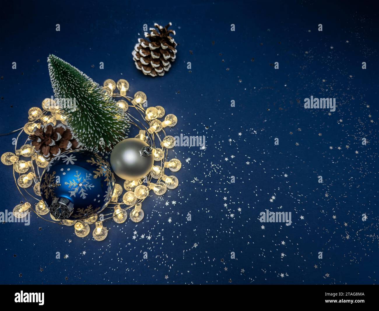 décorations de noël festives avec des lumières de vacances brillantes sur fond bleu foncé avec des confettis argentés. Banque D'Images